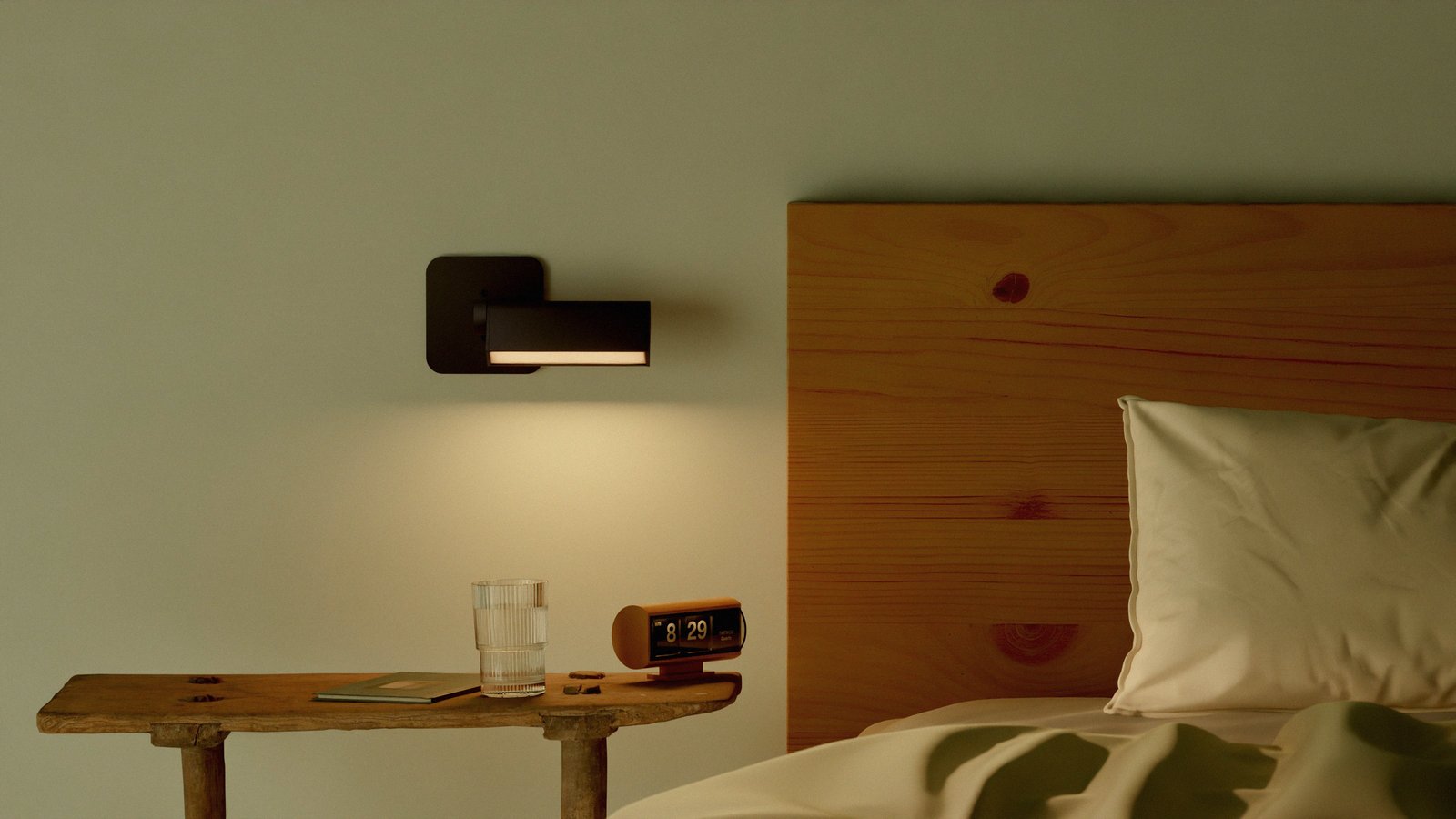 Lambert & Fils Ipoli wall lamp next to a wooden bed and a vintage side table with a vintage 70's italian clock